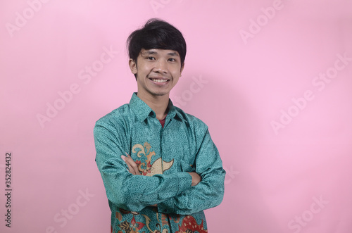 A portrait of young Asian men looking happy. Portrait of young Asian man wearing batik shirt isolated on a pink background
