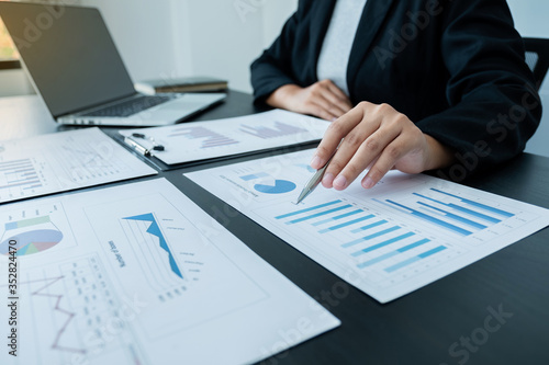 business female is sitting at a desk and calculating financial graph that show results