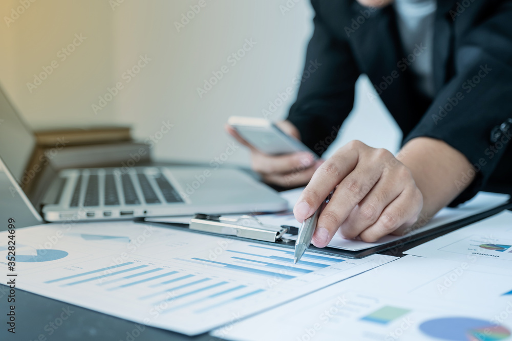 business female is sitting at a desk and calculating financial graph that show results business female is sitting at a desk and calculating financial graph that show results