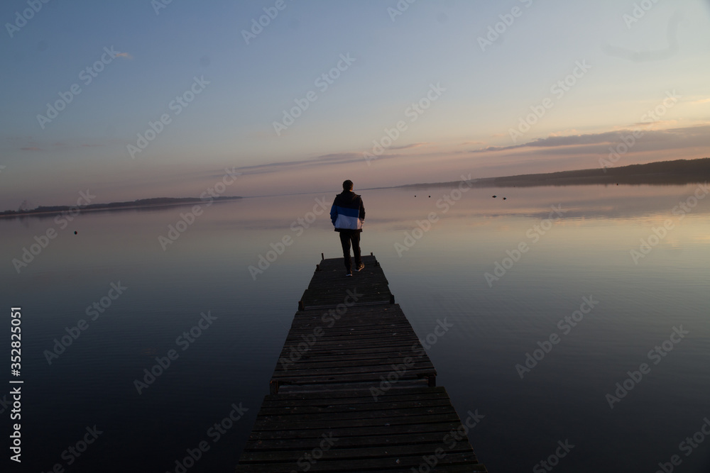Fototapeta premium silhouette of man standing on the pier