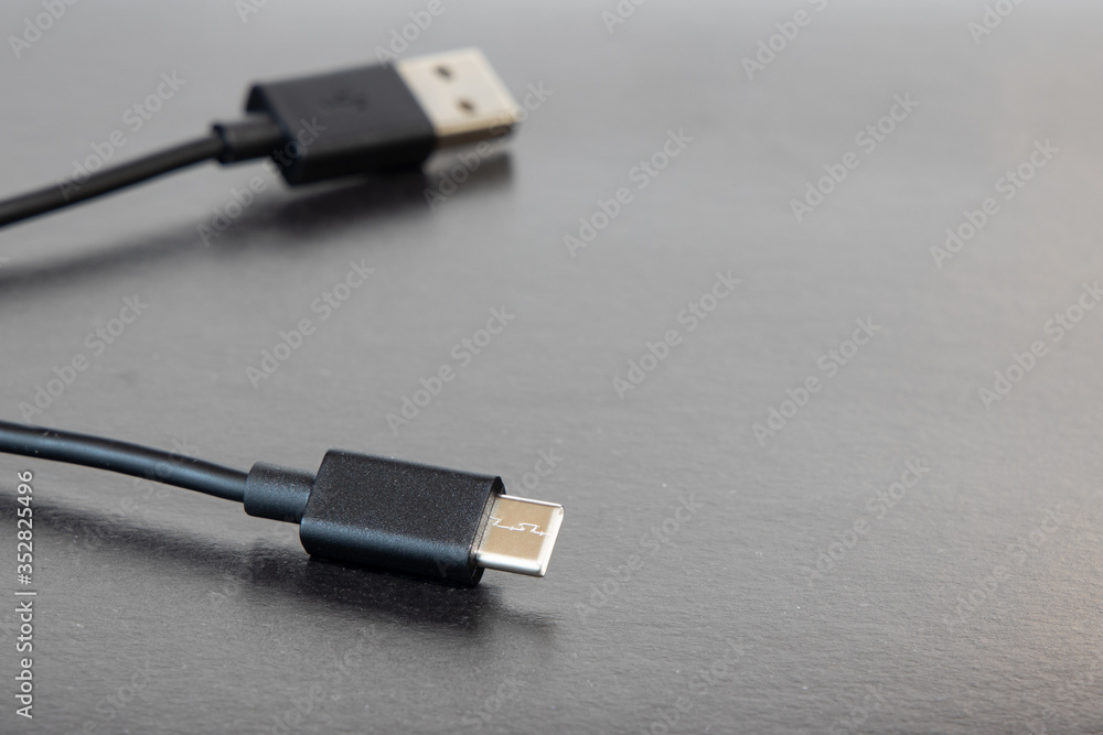 USB charger for phone or another digital gadget on gray neutral dark table background surface with empty copy space for your text USB charger for phone or another digital gadget on gray neutral dark table background surface with empty copy space for your text
