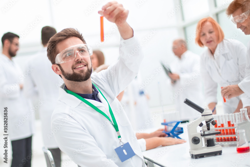 young scientist looking at a test tube with test results. young scientist looking at a test tube with test results.