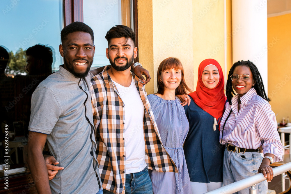 Multiracial young friends posing at the balcony of cafe. Multiracial young friends posing at the balcony of cafe.