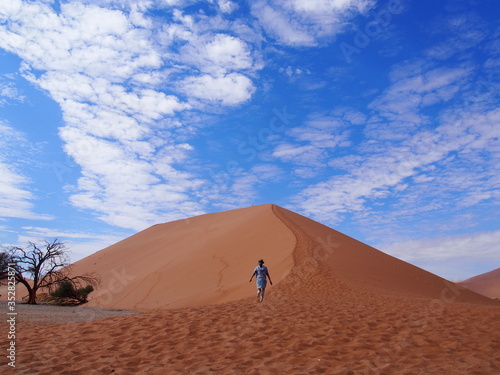 A woman barefoot up a beautiful sand Dune 45, Namibia