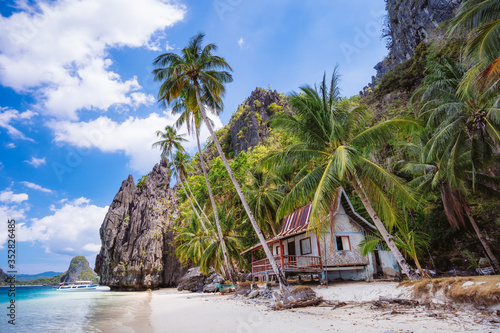 tropical hut under palm trees on Ipil Beach at Pinagbuyutan Island. El Nido, Palawan, Philippines