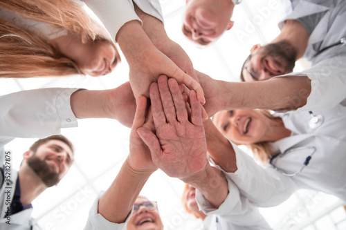 close up. group of different doctors putting their hands together