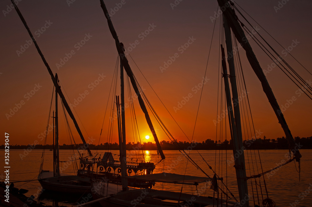 Traditional egyptian felluca sailing boats moored on Nile at sunset