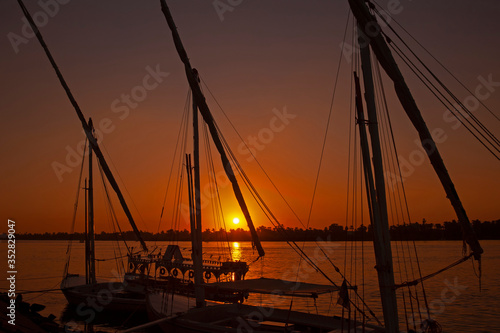 Traditional egyptian felluca sailing boats moored on Nile at sunset