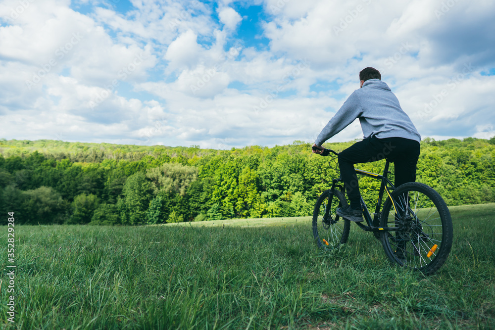 Obraz premium A man on a bicycle resting looks at the nature in the forest on a sunny day