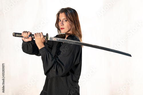 Woman with a black kimono performing martial arts stances with a katana