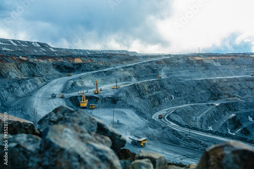 Work of trucks and the excavator in an open pit photo