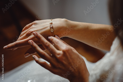 Tablou canvas Beautiful elegant bride puts a bracelet on her hand, closeup