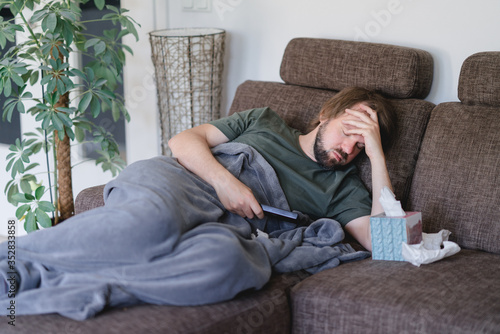 mann liegt erkältet auf der Couchund ist beim fernsehen eingeschlafen