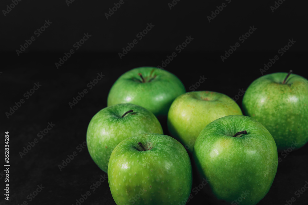 Group of organic green apples on a dark background with place for text. Organic eco food. Healthy diet. Freshly picked vegetables. Natural vitamin C. Some fruits. Farm organic fruits. Group of organic green apples on a dark background with place for text. Organic eco food. Healthy diet. Freshly picked vegetables. Natural vitamin C. Some fruits. Farm organic fruits.