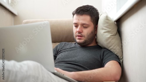 man works hard on modern grey laptop and falls asleep photo