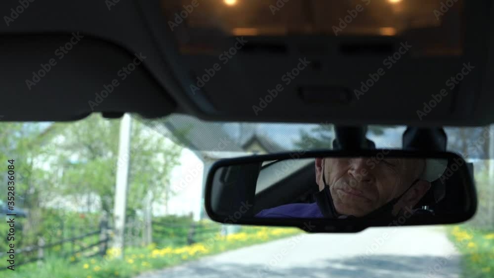 old driver face in black mask reflected in car rear-view mirror against village outside windshield slow motion closeup old driver face in black mask reflected in car rear-view mirror against village outside windshield slow motion closeup