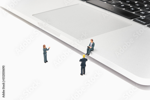 A businesswoman presents to a businessman sitting on a laptop while working on a laptop and another businessman - connectivity and work - Tiny People Working From Home