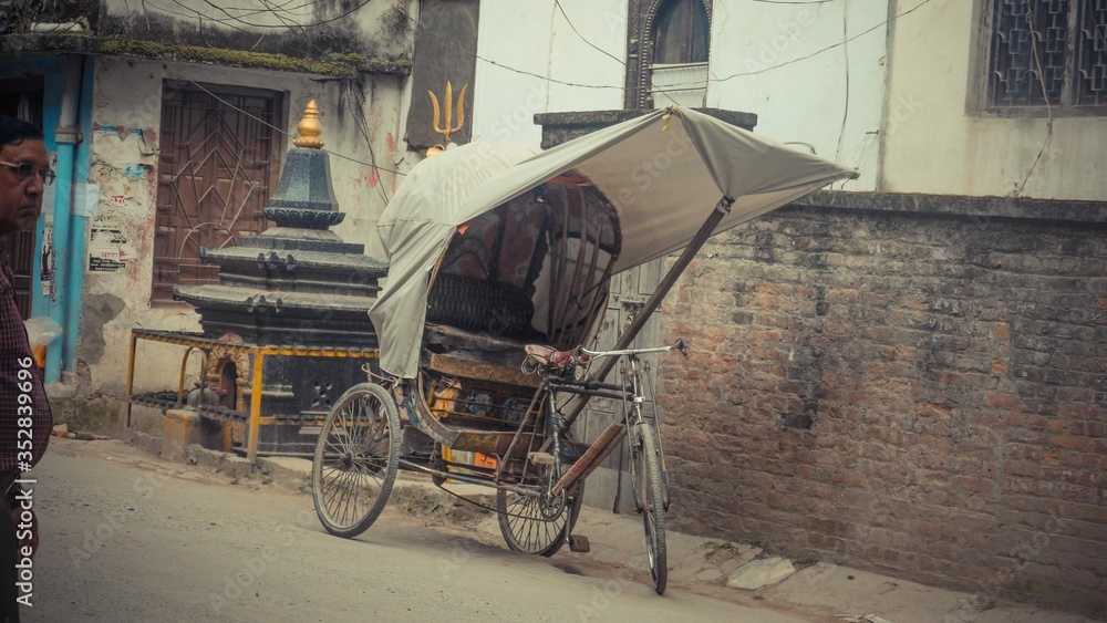 rusty trishaw with white cloth on top parked