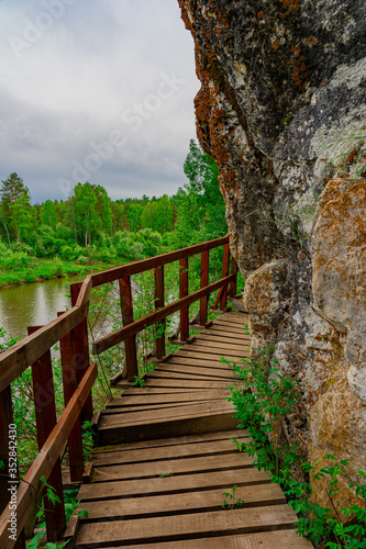 Wooden pathway along a river bank and a rocky cliff