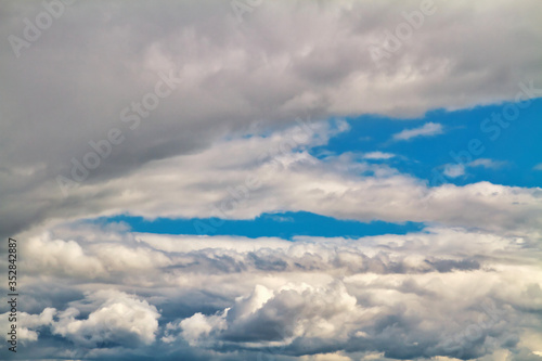 Cloudscape. Blue sky and grey clouds. Sunny day. Cumulus clouds.