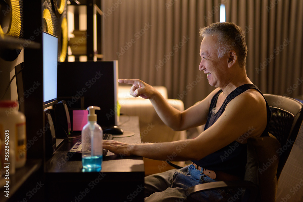 Happy mature Japanese man video calling with computer at home Happy mature Japanese man video calling with computer at home