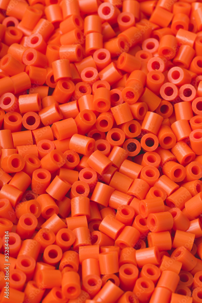 Obraz premium Closeup macro of hundreds of bright orange plastic fuse beads used for kids crafts