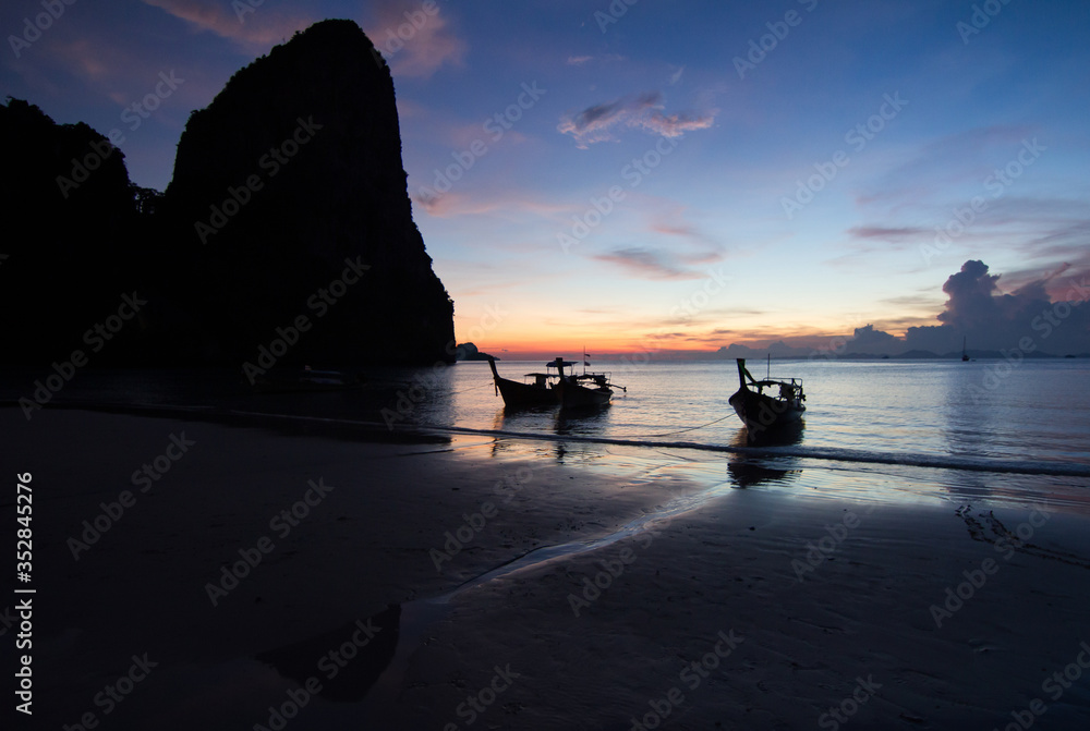 Sunset with longtail boat silhouette in Railay beach, Krabi - Thailand