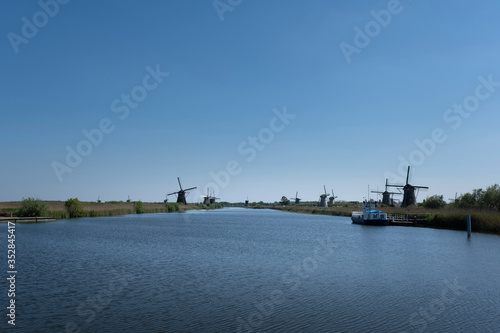 Landscape with beautiful traditional dutch windmills near the water canals with blue sky and clouds reflection in water.
