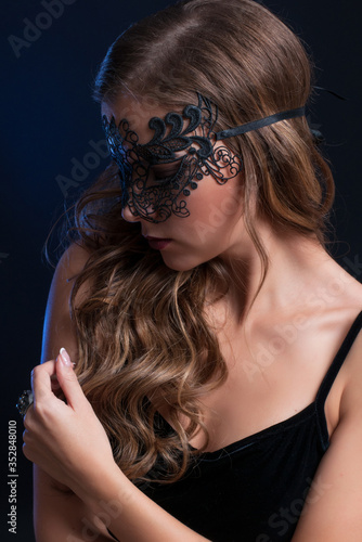 young pretty brunette woman in venetian lacy mask. close up portrait lacy mask. red lips make up. erotic passion woman image on black background