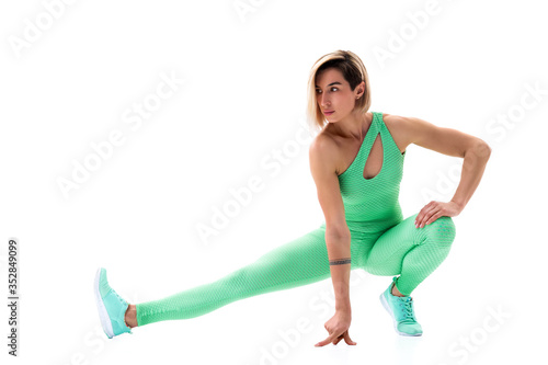 full body portrait of young sporty woman stretching before exercise isolated on white background.