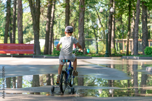 Wallpaper Mural Child rides bike on road in park, rear view Torontodigital.ca