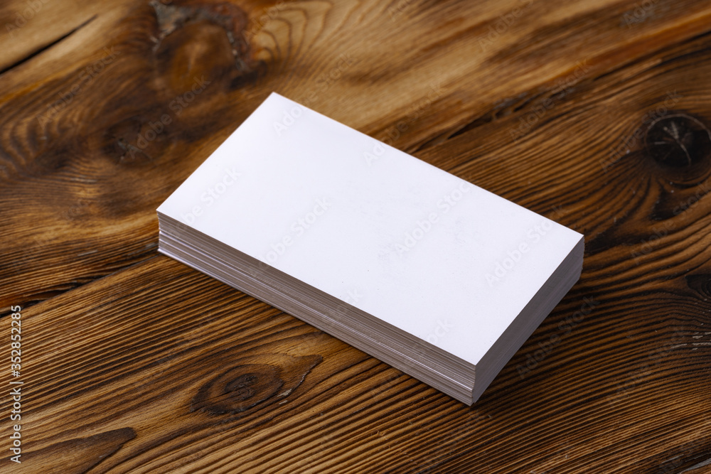 Fototapeta premium Stack of white business cards on brown wooden background