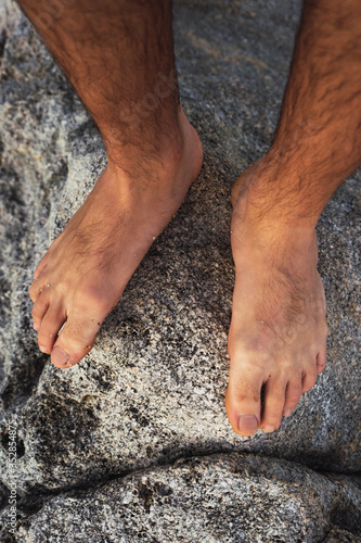 Stock photo of man's feet on top of a rock eroded by the sea