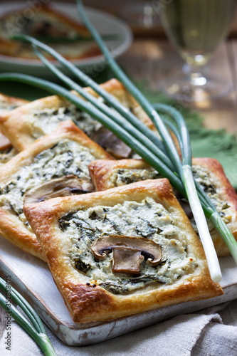 Puffs with cheese, spinach and mushrooms, served with wine and green onions. Rustic style. photo