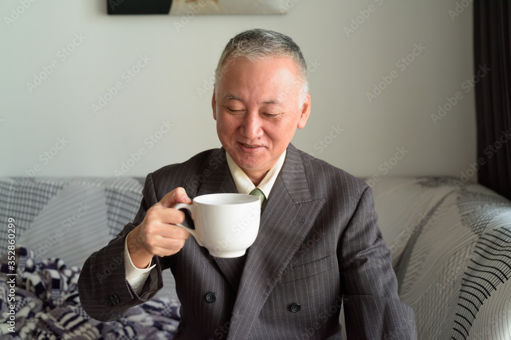 Happy mature Japanese businessman drinking coffee at home Happy mature Japanese businessman drinking coffee at home