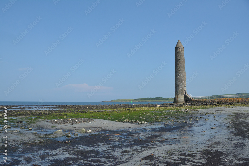Fototapeta premium Old Lighthouse on the shore. The Chaine Memorial Tower in Larne, County Antrim, Northern Ireland.