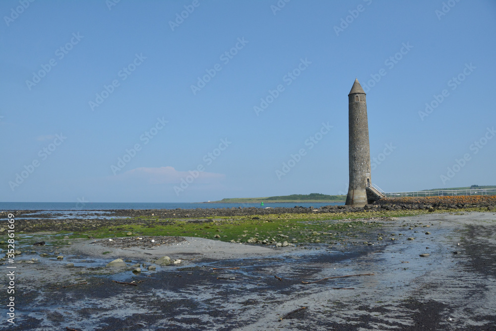 Old Lighthouse on the shore. The Chaine Memorial Tower in Larne, County Antrim, Northern Ireland.
