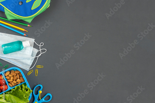School the new reality global pandemic coronavirus covid-19 to school, tools, notebook, medicine mask, sanitizer, school lunch box  on blue background, stylish banner flyer, flat lay, top view