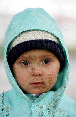 Portrait of a little boy with a dirty face in a hood