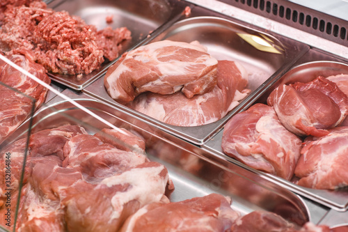 Obraz na płótnie Heap of fresh meat food meat food background in supermarket store. Different types of raw meat in plastic boxes, leg of lamb on the bone, beef tail, beef neck, beef blade. Concept of farm and raw w salonie
