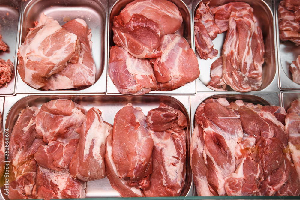 Heap of fresh meat food meat food background in supermarket store. Different types of raw meat in plastic boxes, leg of lamb on the bone, beef tail, beef neck, beef blade. Concept of farm and raw Heap of fresh meat food meat food background in supermarket store. Different types of raw meat in plastic boxes, leg of lamb on the bone, beef tail, beef neck, beef blade. Concept of farm and raw