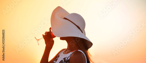  Summer time. Woman in big hat with glasswine on sunset beach. photo