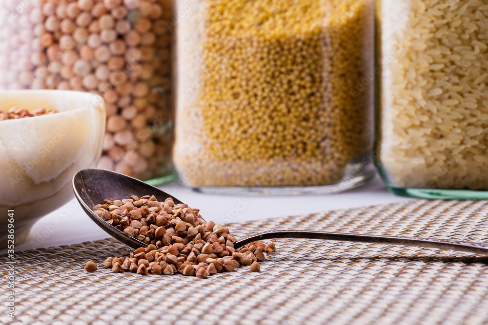 Raw dry buckwheat grain in a bowl with a spoon close-up. Raw dry buckwheat grain in a bowl with a spoon close-up.