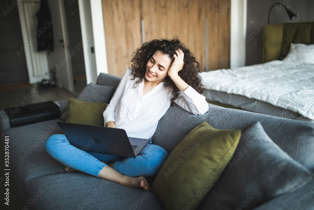 Happy pretty woman using laptop sitting on sofa Happy pretty woman using laptop sitting on sofa