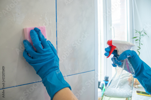 the girl washes the wall tile with a sponge and a special liquid. Cleaning the bathroom with cleaning products