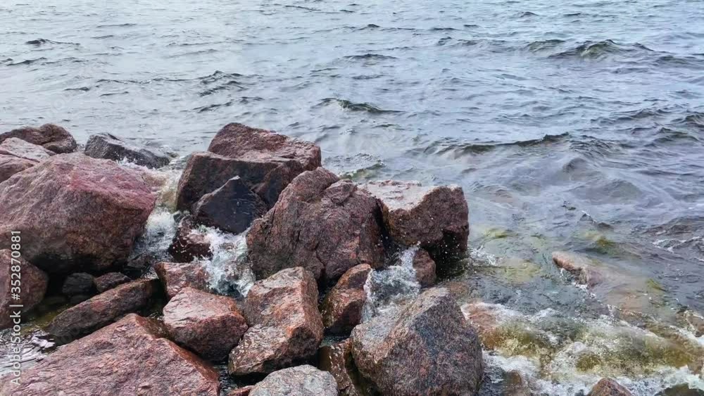 The rocky shore of the ocean. Beautiful sea with small waves. Waves run up to the stones. Sea background. The rocky shore of the ocean. Beautiful sea with small waves. Waves run up to the stones. Sea background.
