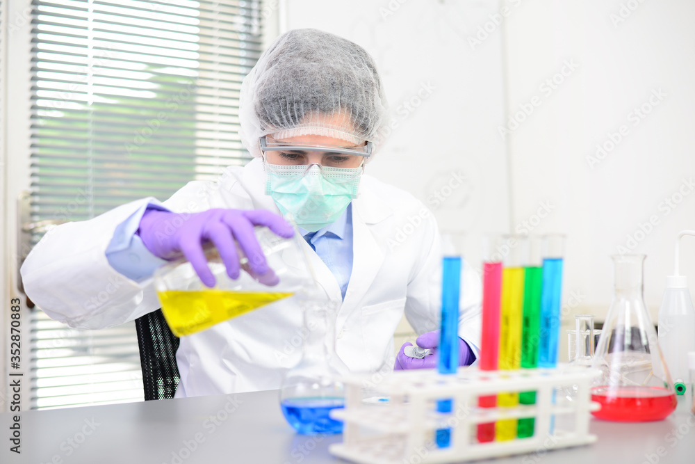 Young doctor scientist in the laboratory making experience research about covid19 coronavirus vaccine wearing white lab coat a mobcap and surgical mask Young doctor scientist in the laboratory making experience research about covid19 coronavirus vaccine wearing white lab coat a mobcap and surgical mask