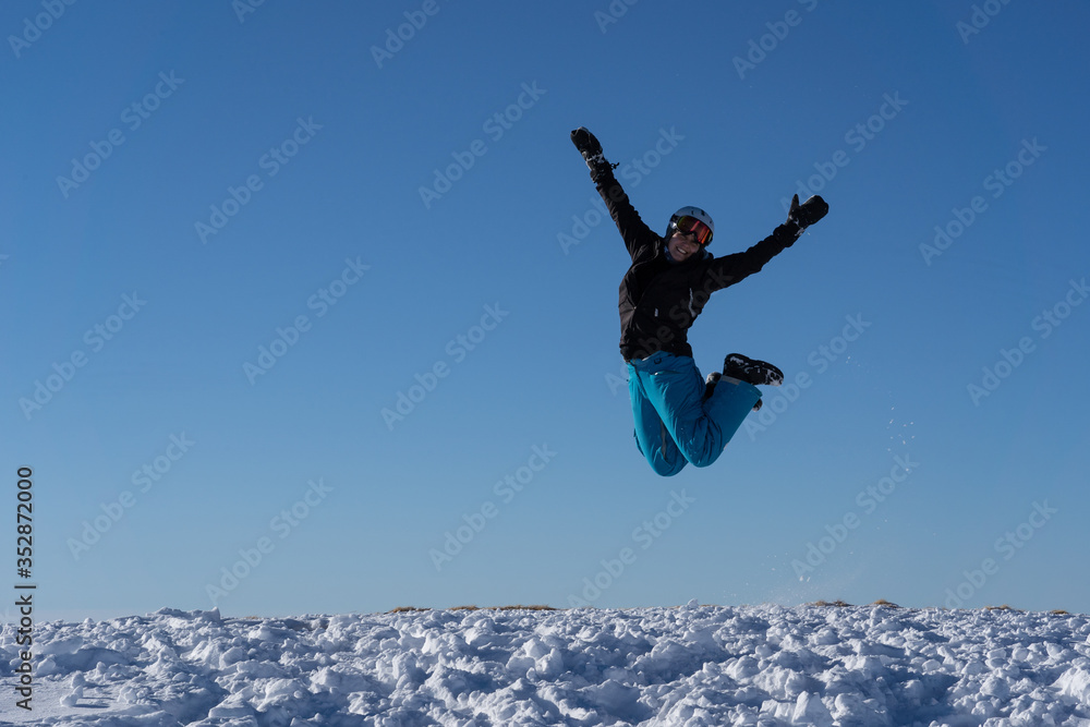 Girl with goggles and helmet is leaping midair in winter. Girl with goggles and helmet is leaping midair in winter.