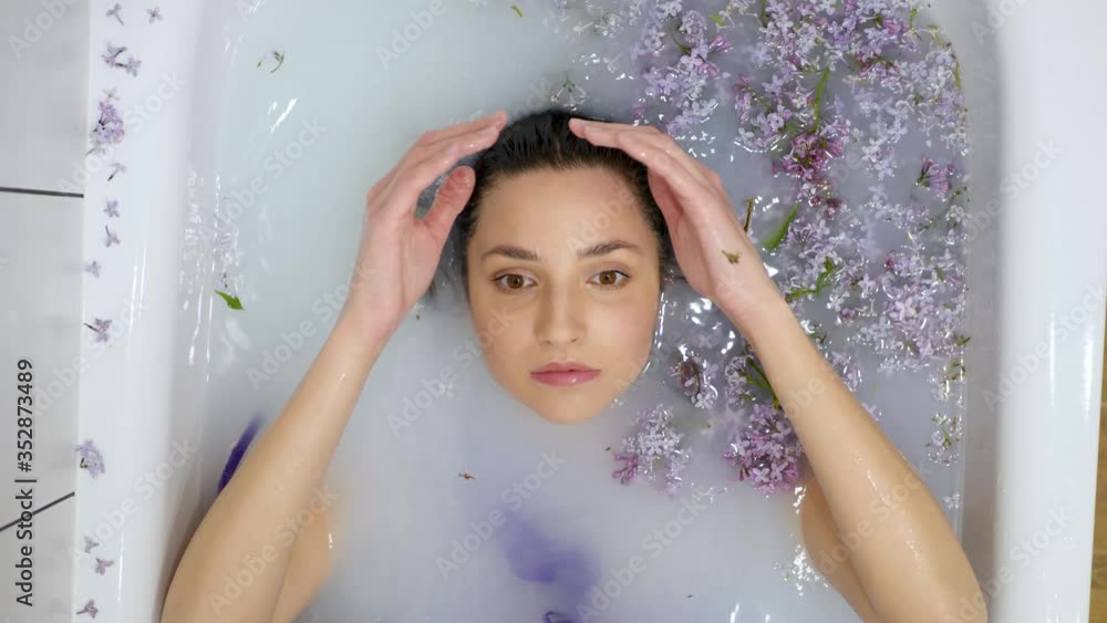 sexy beautiful healthy woman lies in a milk bath with lilac flowers during spa sexy beautiful healthy woman lies in a milk bath with lilac flowers during spa