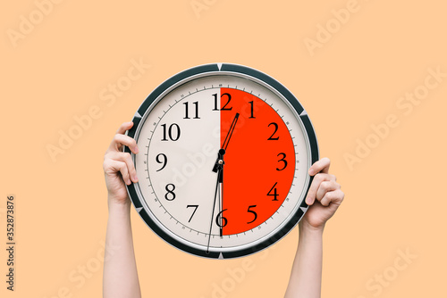 Women's hands hold a round black watch, showing half an hour. Dial and hands. Lunch break, meeting, or time planning